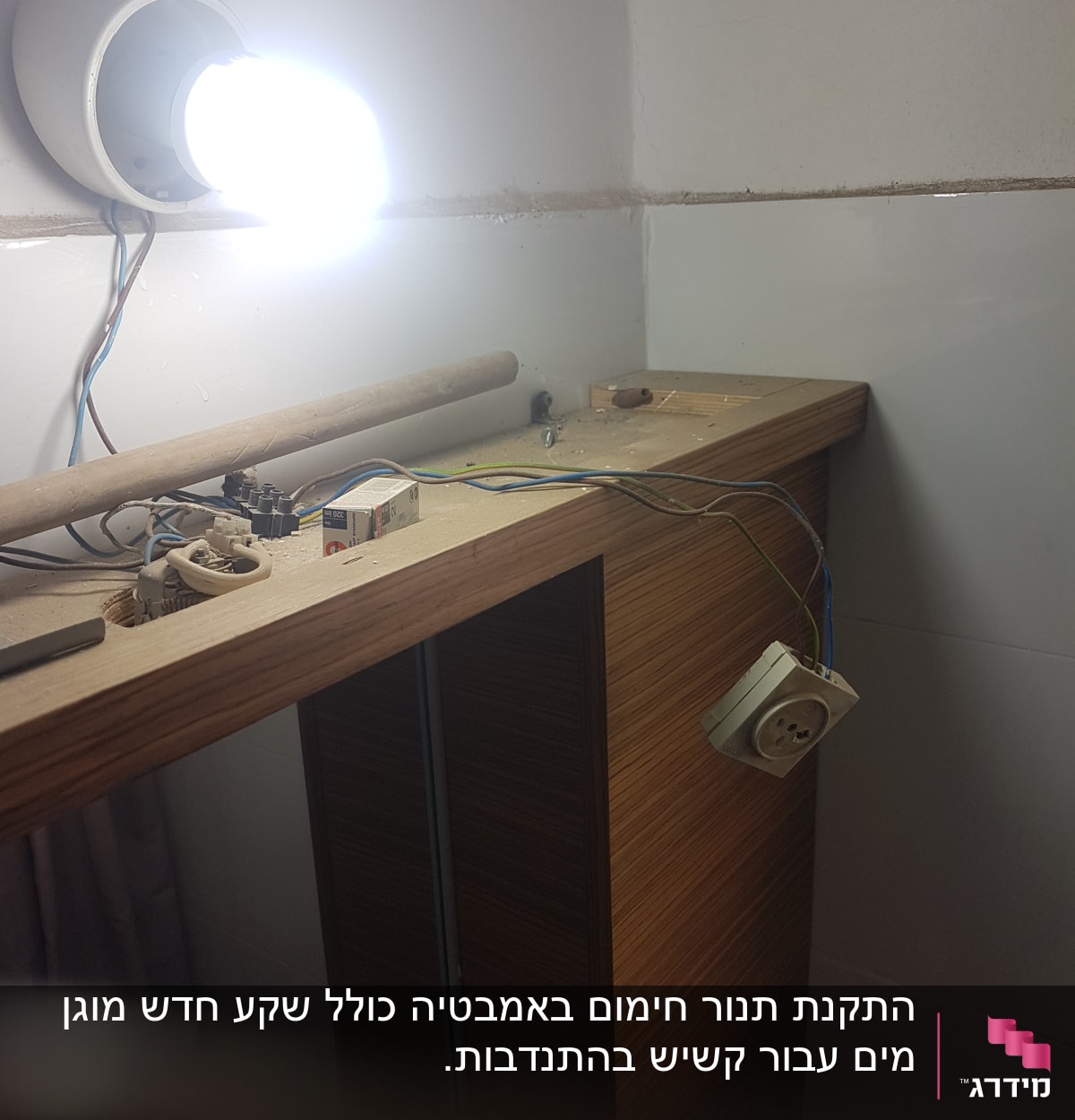 מנורה דולקת, חוטי חשמל ושקע חשמלי על שולחן עץ